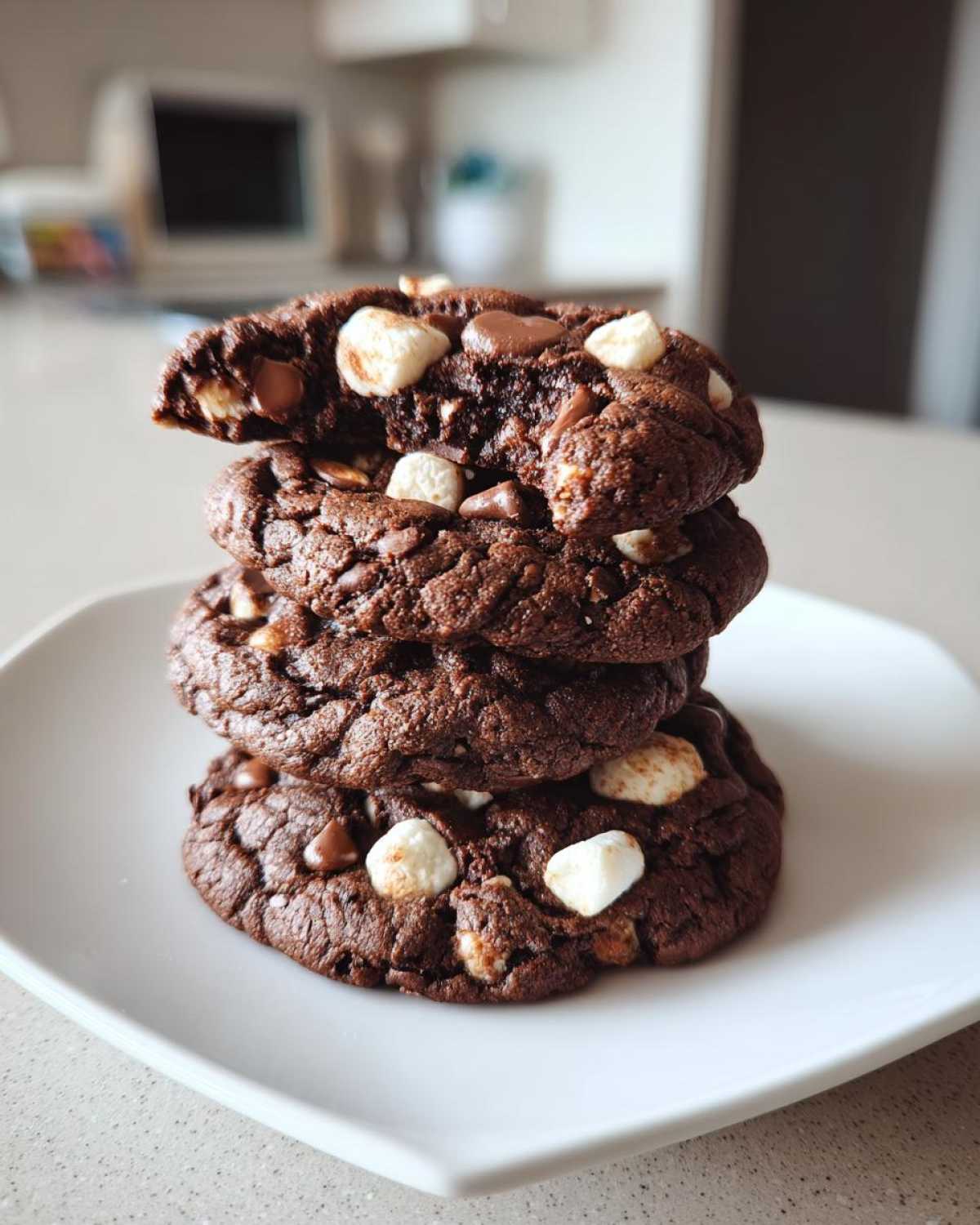 A stack of three rich, dark hot chocolate cookies loaded with chocolate chips and mini marshmallows.