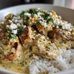 Close-up of a creamy street corn chicken rice bowl topped with cotija cheese and cilantro.