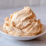 A generous serving of light, fluffy, whipped cinnamon butter piled high in a small white bowl.