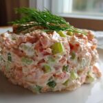 A molded portion of creamy salmon salad mixed with celery and topped with fresh dill.