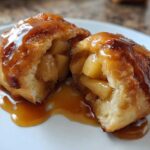 Close-up of an amazing 1-step apple dumpling cut in half, showing spiced apple filling and caramel sauce.