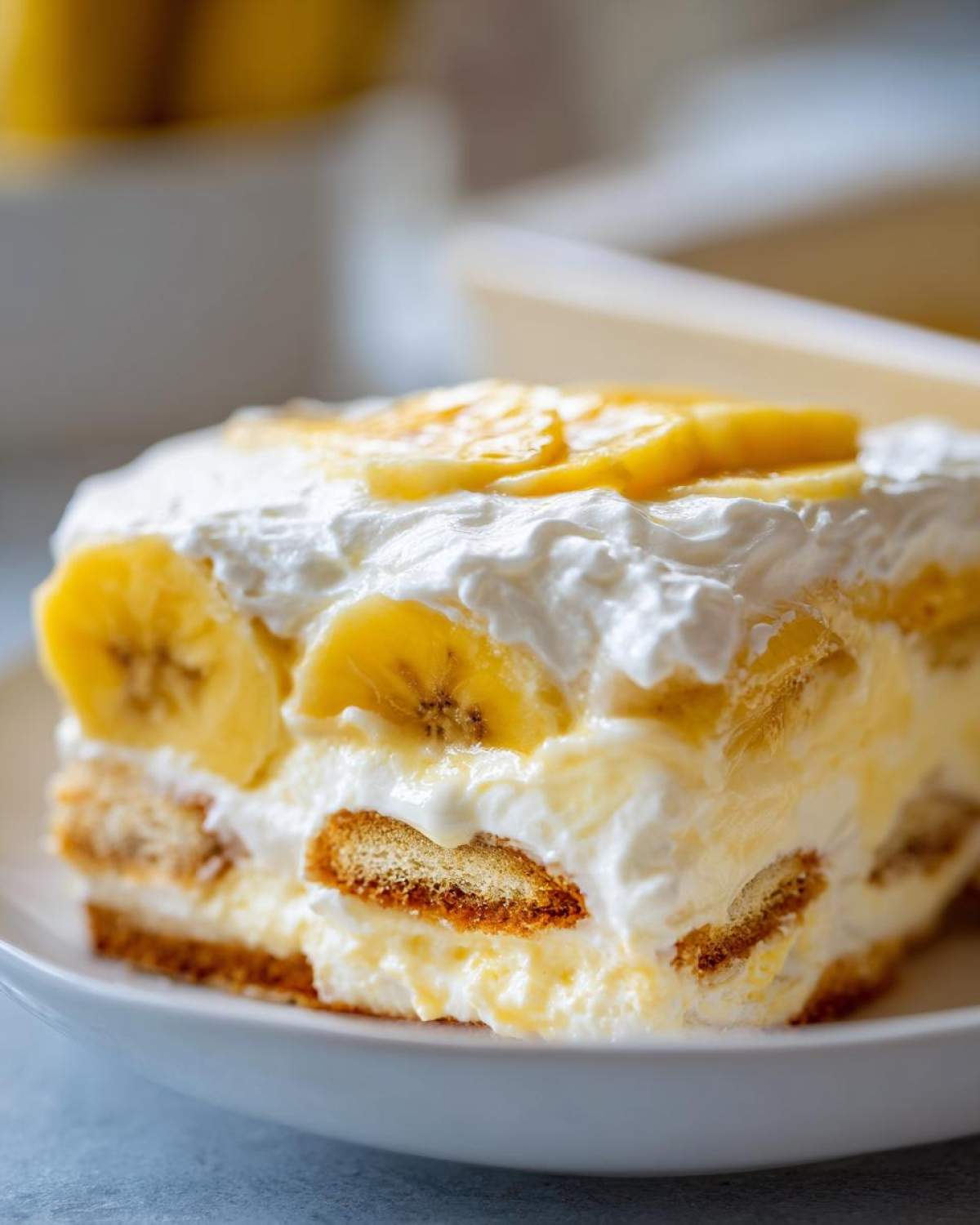 Close-up of a layered slice of amazing banana pudding featuring vanilla wafers, cream, and fresh banana slices.