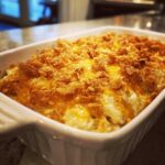 Close-up of a creamy potato casserole topped with melted cheddar cheese and crunchy cornflakes.