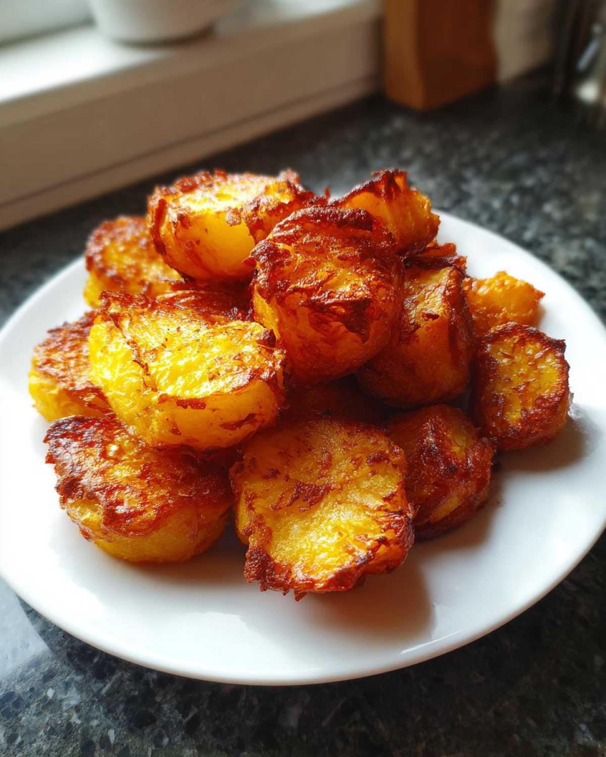 A pile of golden brown, crispy roast potatoes served on a white plate, showcasing their perfect texture.
