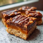 Close-up of a delicious twix cookies bar showing a shortbread base, thick caramel layer, and chocolate topping with nuts.