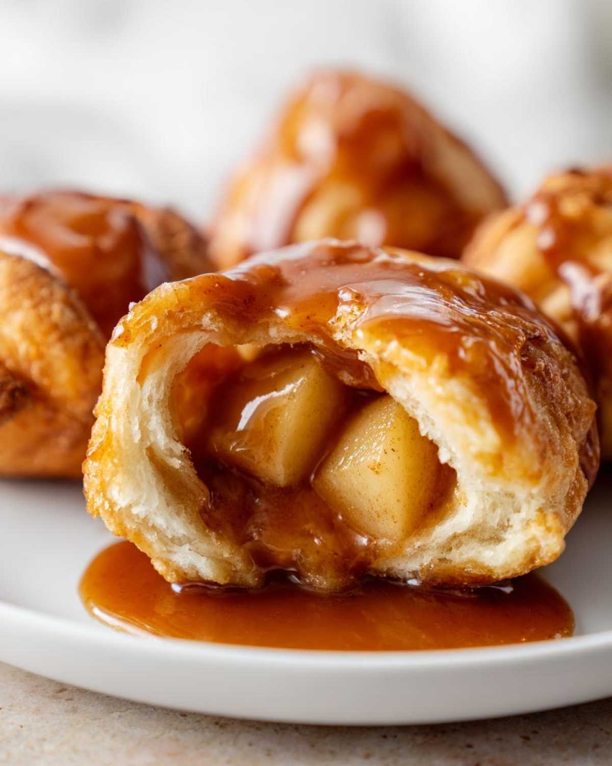 Cross-section of a gooey apple dumpling showing spiced apple chunks and rich caramel sauce.