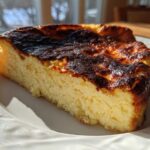 A close-up slice of basque cheesecake showing its creamy interior and signature dark, caramelized top.