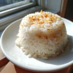 A perfectly molded serving of fluffy white butter rice topped with golden brown toasted garlic or seasoning.