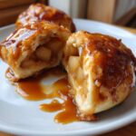 A delicious apple dumpling cut open to show warm, spiced apple filling, drizzled with caramel sauce.