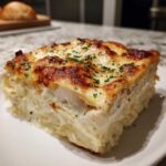 A thick, square slice of rich chicken alfredo lasagna with layers of pasta, creamy sauce, and chicken, topped with browned cheese and parsley.