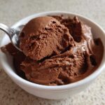 A spoonful of rich, airy chocolate mousse being lifted from a white bowl.