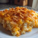A serving of creamy potato casserole topped with melted cheddar cheese and crispy cornflakes.
