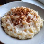Close-up of a bowl of creamy rice pudding recipe generously dusted with ground cinnamon.