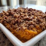 Close-up of a rich, orange easy sweet potato casserole topped generously with a brown sugar and pecan crumble.