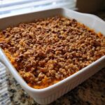 A baked easy sweet potato casserole in a white dish topped with a crunchy pecan streusel.