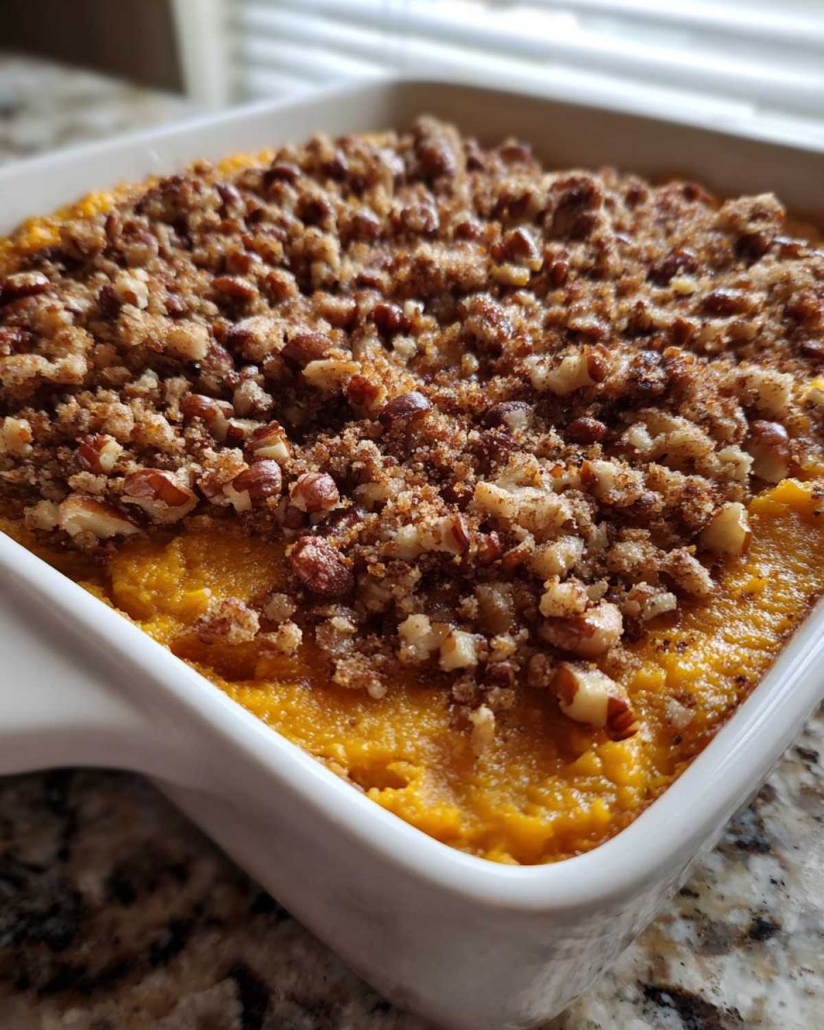 A close-up view of an easy sweet potato casserole topped with a crunchy pecan and brown sugar streusel.