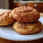 Three soft, chewy snickerdoodles generously coated in cinnamon sugar, stacked on a white plate.