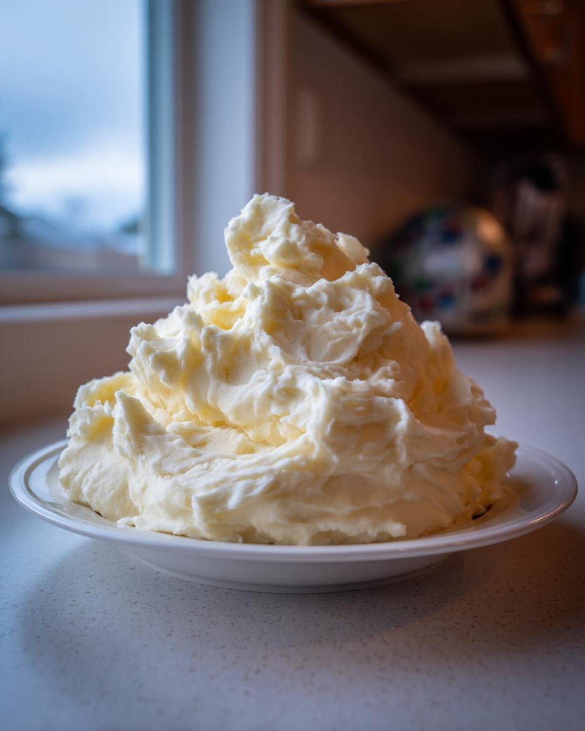 A large, fluffy mound of creamy, buttery mashed potatoes served on a white plate.