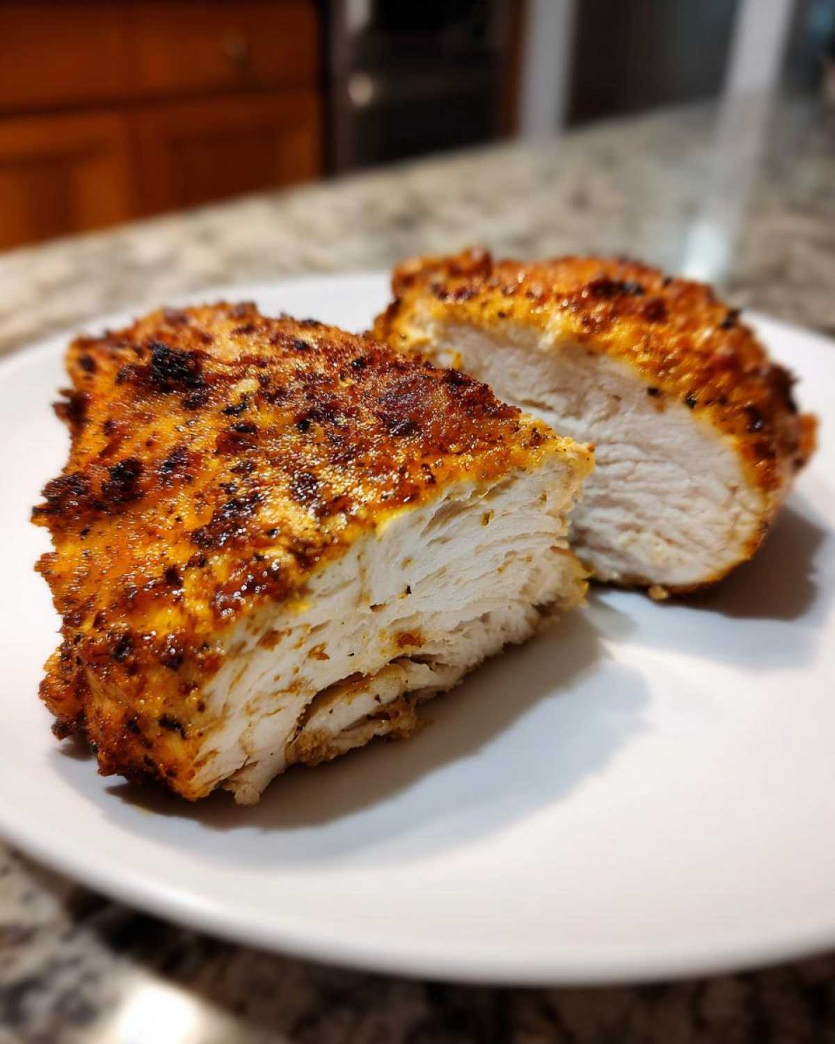 Cross-section of juicy baked ranch chicken showing white, moist interior and seasoned crust.