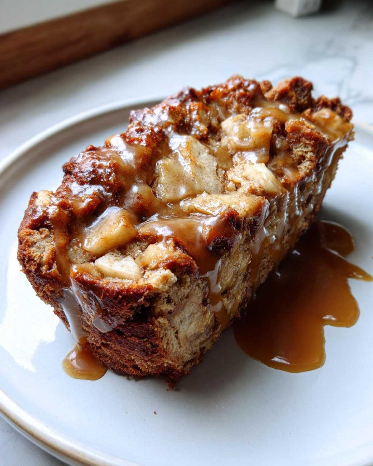 A moist slice of apple dapple cake topped generously with chunks of apple and drizzled with rich caramel sauce.
