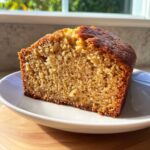 Close-up of a thick slice of moist greek yogurt banana bread with a golden-brown crust.
