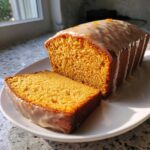A slice cut from a moist sweet potato pound cake topped with a vanilla glaze and orange zest.