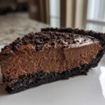 A rich slice of chocolate mousse pie with a dark crust, topped with chocolate crumbs.
