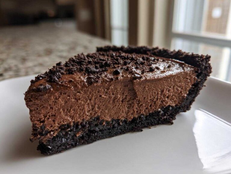 A rich slice of chocolate mousse pie with a dark crust, topped with chocolate crumbs.