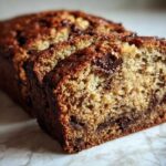 Close-up of sliced vegan banana bread loaf showing moist crumb and melted chocolate chips.