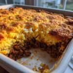 Close-up of a baked sloppy joe cornbread casserole showing the golden crust and savory meat layer.