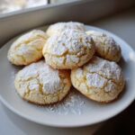 A plate piled high with soft, crinkle-topped cool whip cookies generously dusted with powdered sugar.