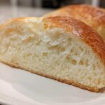 Close-up of a slice showing the fluffy, white interior crumb of condensed milk bread.