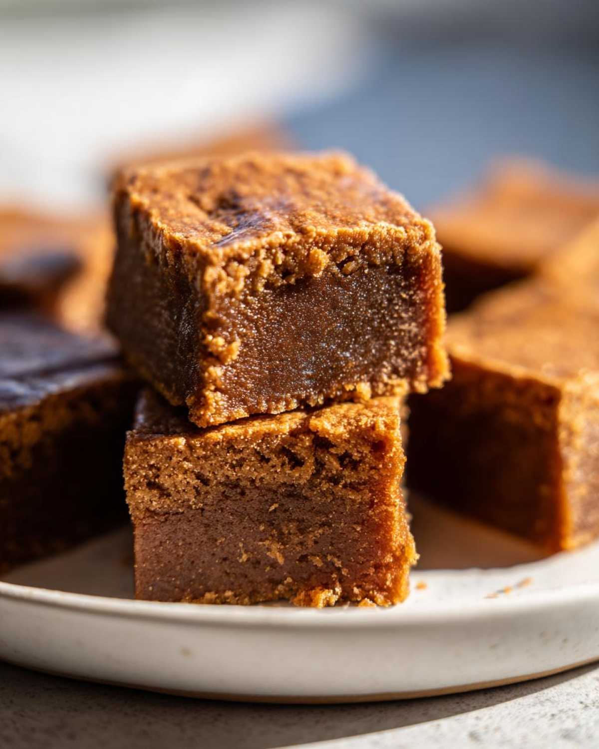 Two stacked, rich brown squares of homemade penuche fudge showing a dense, slightly grainy texture.