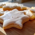 Close-up of star-shaped sugar cookies decorated with glossy white sugar cookie icing recipe.