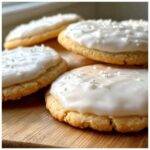 Close-up of soft sugar cookies topped with thick, glossy white icing from the sugar cookie icing recipe.
