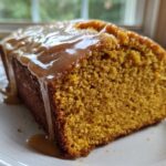 Close-up of a moist slice of sweet potato pound cake drizzled with a thick caramel glaze.