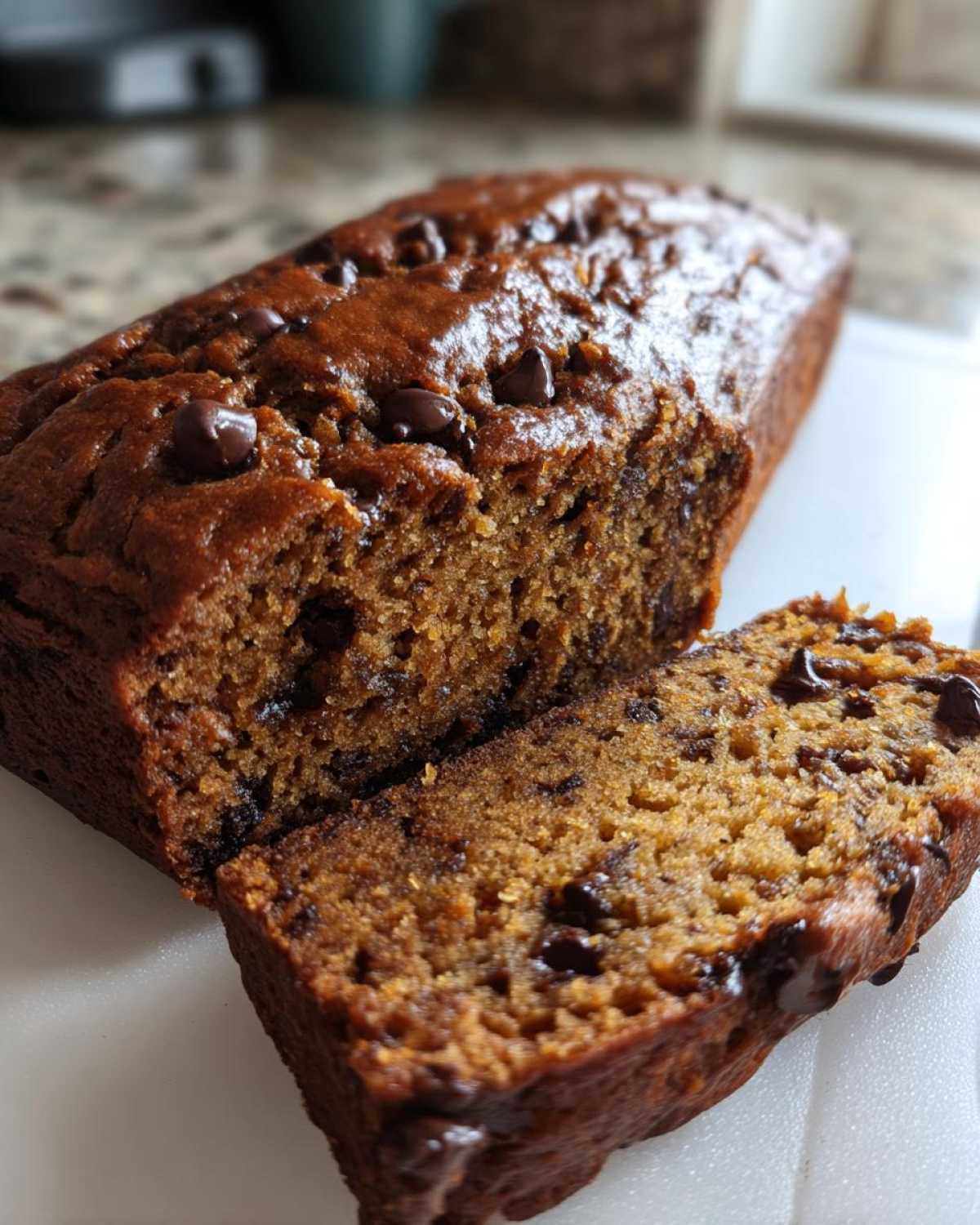 Close-up of a freshly baked vegan banana bread loaf, sliced to show moist interior and chocolate chips.