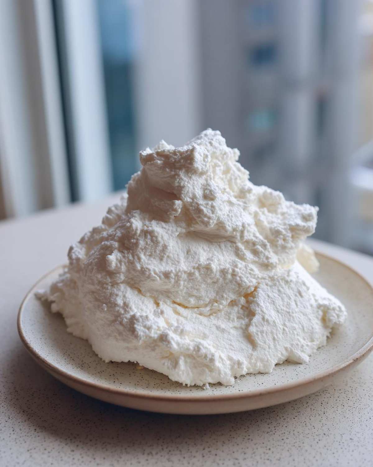 A large mound of bright white, fluffy material resembling whipped cream, representing the 2-Ingredient Fluffy Cloud Dough.
