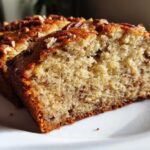 Close-up of two slices of moist Air Fryer Banana Bread with Pecans on a white plate.