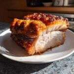 A thick slice of juicy Air Fryer Pork Joint with incredibly crispy, golden-brown crackling resting on a white plate.