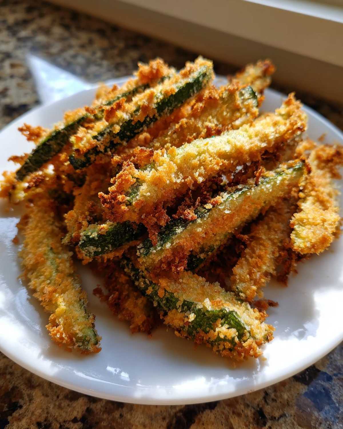 A plate piled high with golden brown Air Fryer Zucchini Fries with Panko, showing crispy texture.