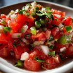 Close-up of vibrant, freshly chopped Authentic Pico de Gallo with fresh jalapeño, tomatoes, and onion in a white bowl.