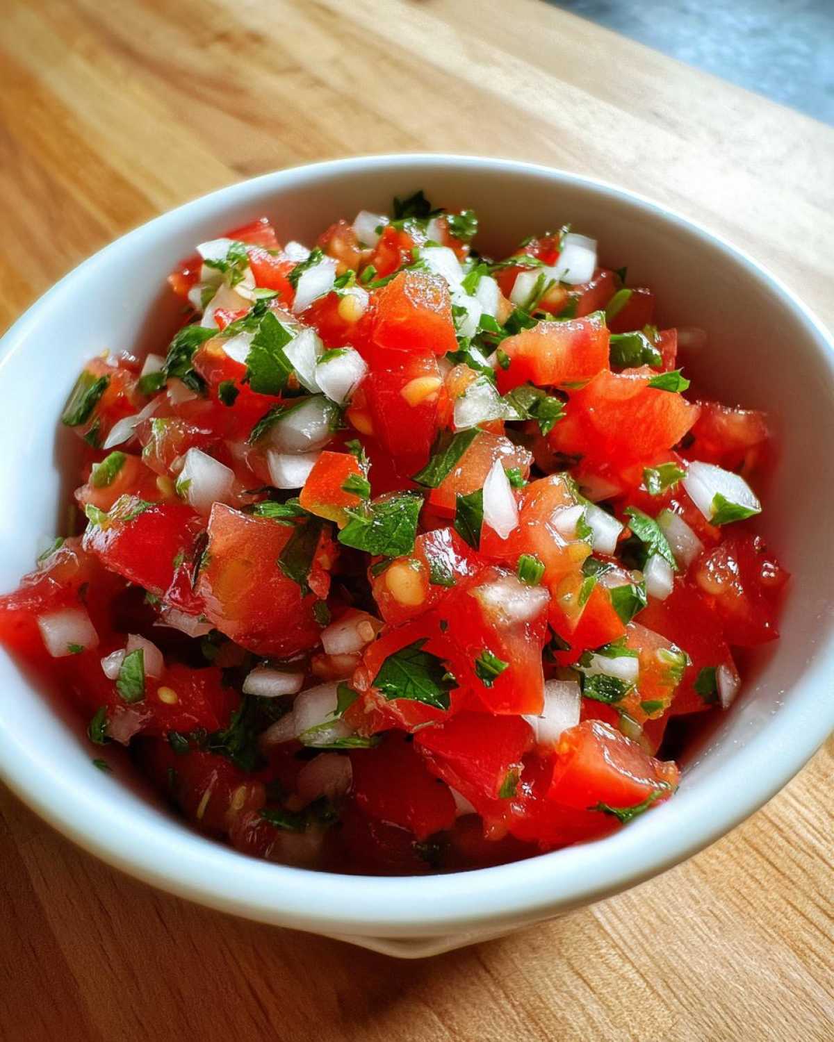 Close-up of fresh Authentic Pico de Gallo with Lime, featuring diced tomatoes, white onion, and cilantro in a white bowl.