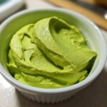 Close-up of bright green, creamy Avocado Crema with Lime and Cilantro swirled in a small white ramekin.