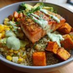 Close-up of a vibrant BBQ Salmon Bowl featuring a piece of glazed salmon over quinoa, roasted sweet potato, corn, and avocado slices.