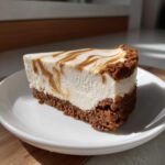 A close-up of a slice of Biscoff Greek Yogurt Cheesecake Hack with a thick crust and Biscoff swirl topping.