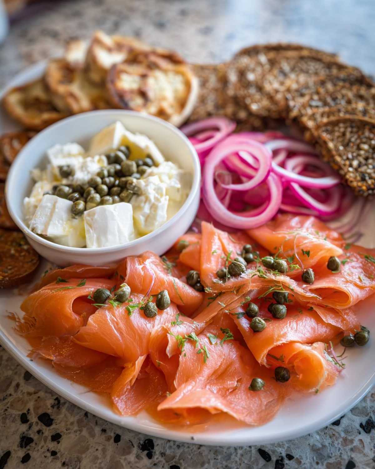 Close-up of a Breakfast Grazing Board with Smoked Salmon, cream cheese, capers, and red onion slices.