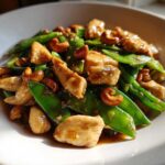 Close-up of glistening Cashew Chicken Stir-Fry with Snap Peas coated in savory brown sauce.