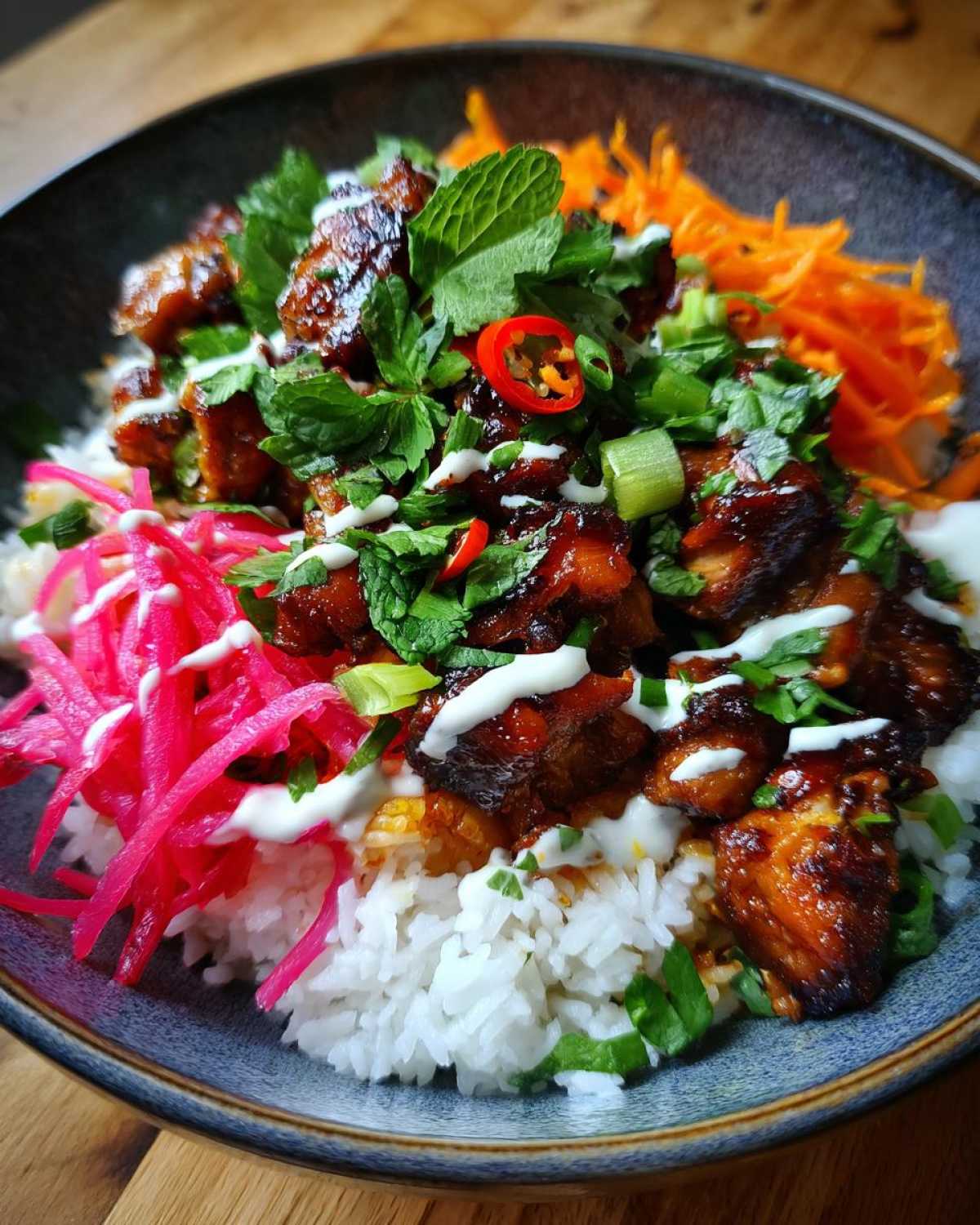 Close-up of a Chicken Banh Mi Bowls with rice, glazed chicken, bright pink pickled vegetables, and fresh herbs.