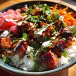 Close-up of a vibrant Chicken Banh Mi Bowl featuring glazed chicken pieces over rice, topped with pickled vegetables and fresh mint.